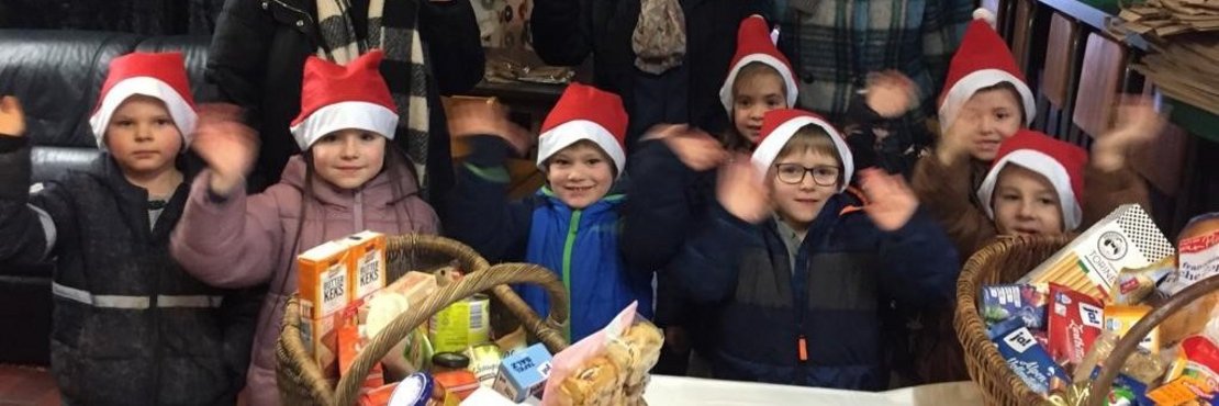 Kinder und Erwachsene mit Nikolausmützen und Körben gefüllt mit Lebensmitteln