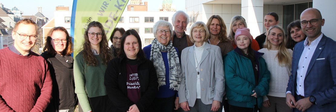 Eine Gruppe von Menschen steht vor einem Banner des Rhein-Kreis Neuss, der als Fairtrade-Kreis ausgezeichnet wurde.