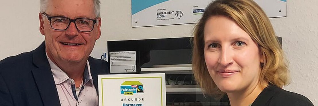 Ein Mann und eine Frau halten die Urkunde zur Zertifizierung hoch.