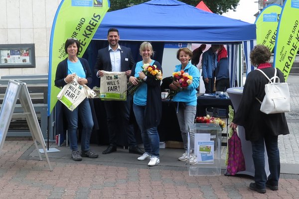 Personengruppe vor einem Präsentationsstand zum Thema Fairtrade