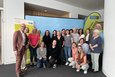 Das Foto zeigt eine Gruppe von ungefähr zwanzig Personen, die meisten Frauen, die sich vor einem hellblauen Banner mit dem Logo „Rhein Kreis Neuss“ und der Webseite www.rhein-kreis-neuss.de aufgestellt haben.