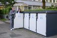 Eine Frau und ein Mann stehen an grau-weißen Fahrradboxen.