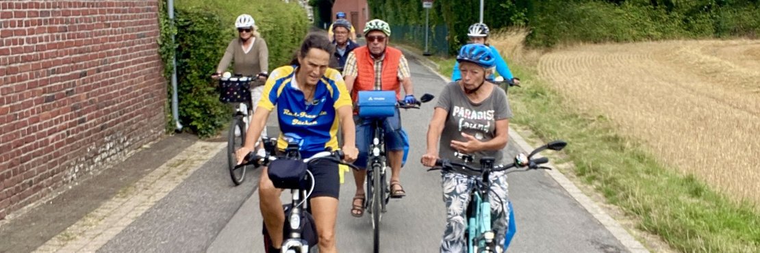 Auf dem Bild ist eine Gruppe von Radfahrern zu sehen, die auf einem Feldweg fahren.