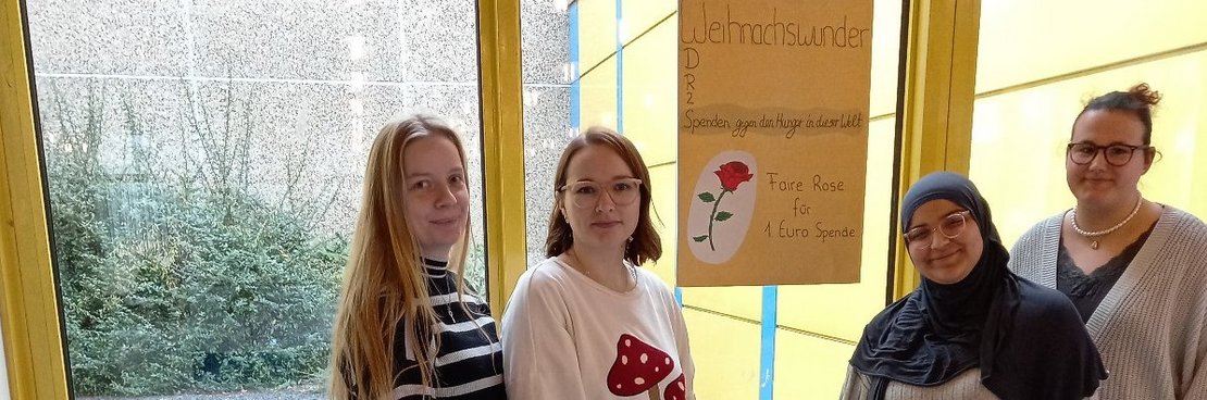 Vier Schülerinnen hinter einem Tisch voll Rosen.