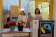 Vier junge Frauen hinter einem Tisch, auf dem Rosen stehen.