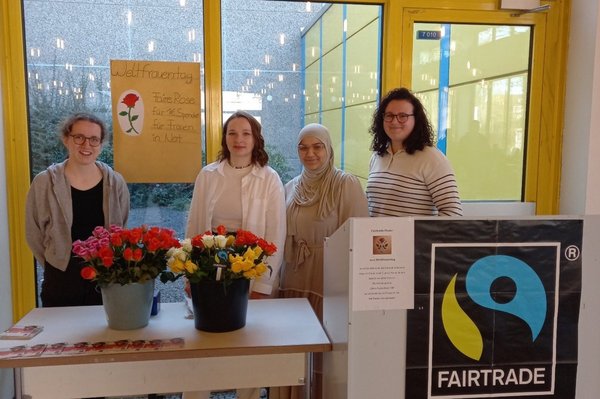 Vier junge Frauen hinter einem Tisch, auf dem Rosen stehen.